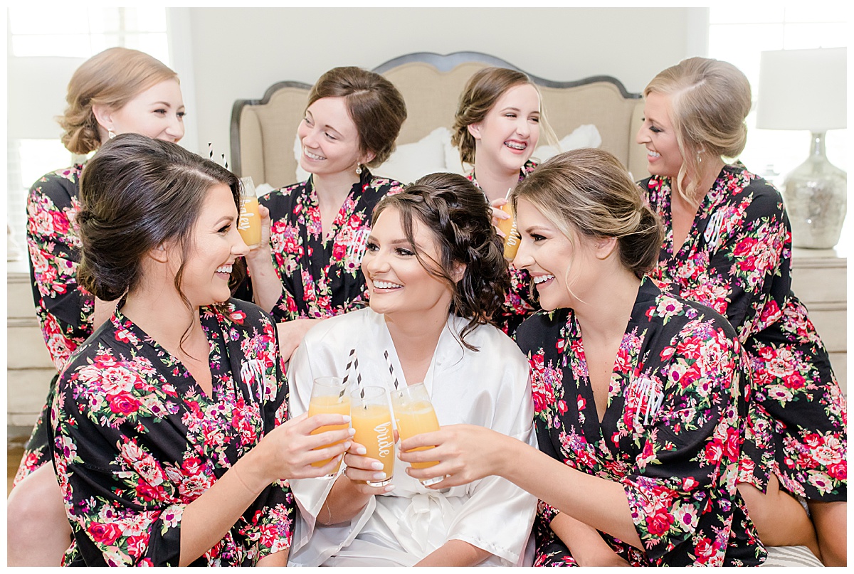 bride and bridesmaids in floral robes drinking mimosas