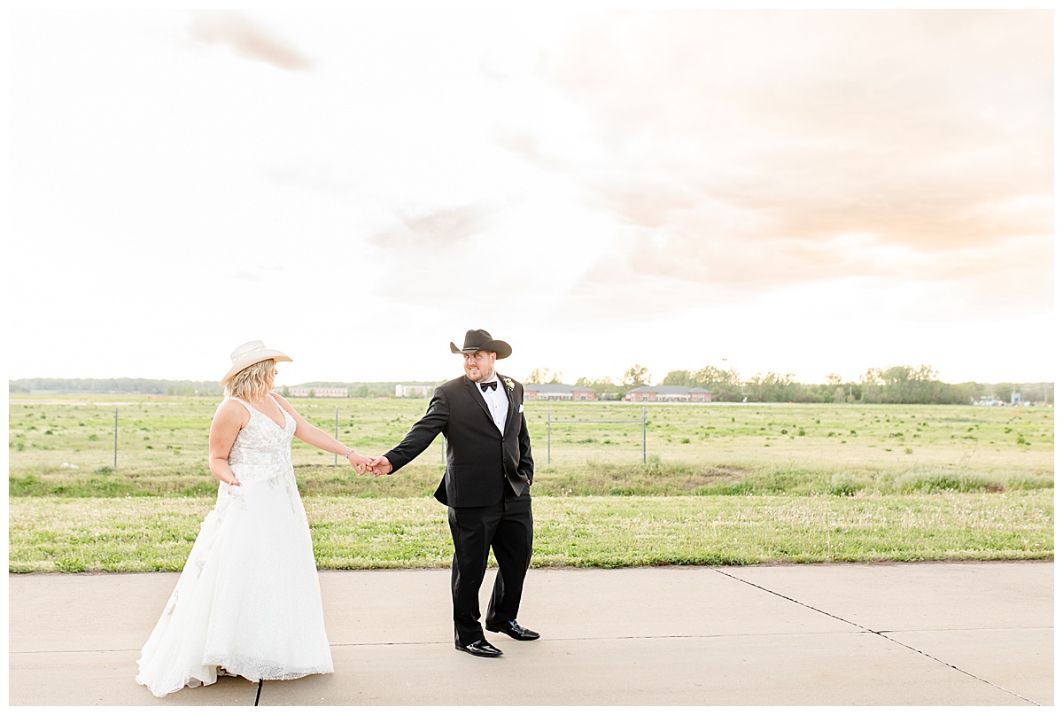 bride and groom walking on airplane runway