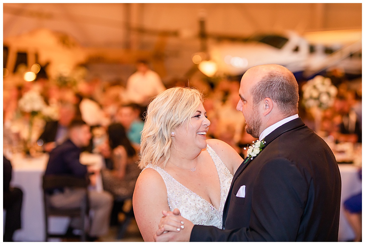 bride and groom first dance at airplane hangar reception