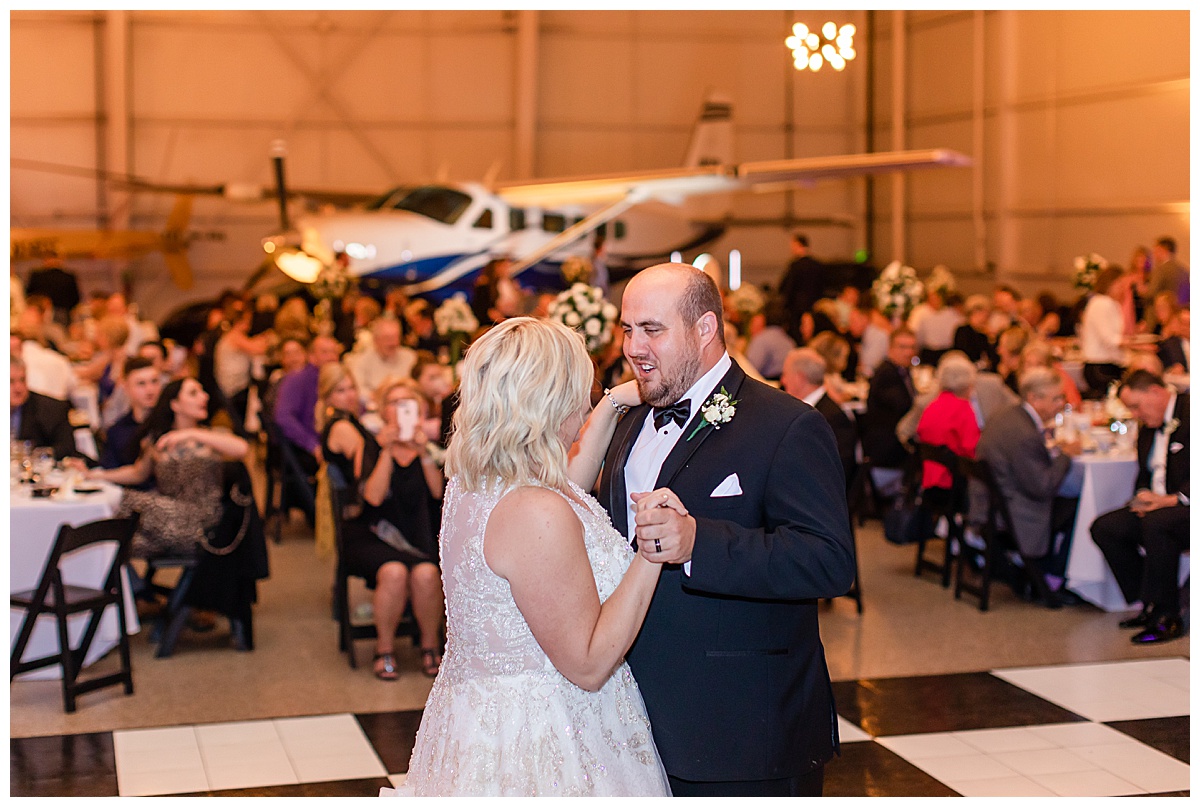 bride and groom first dance with airplane in background