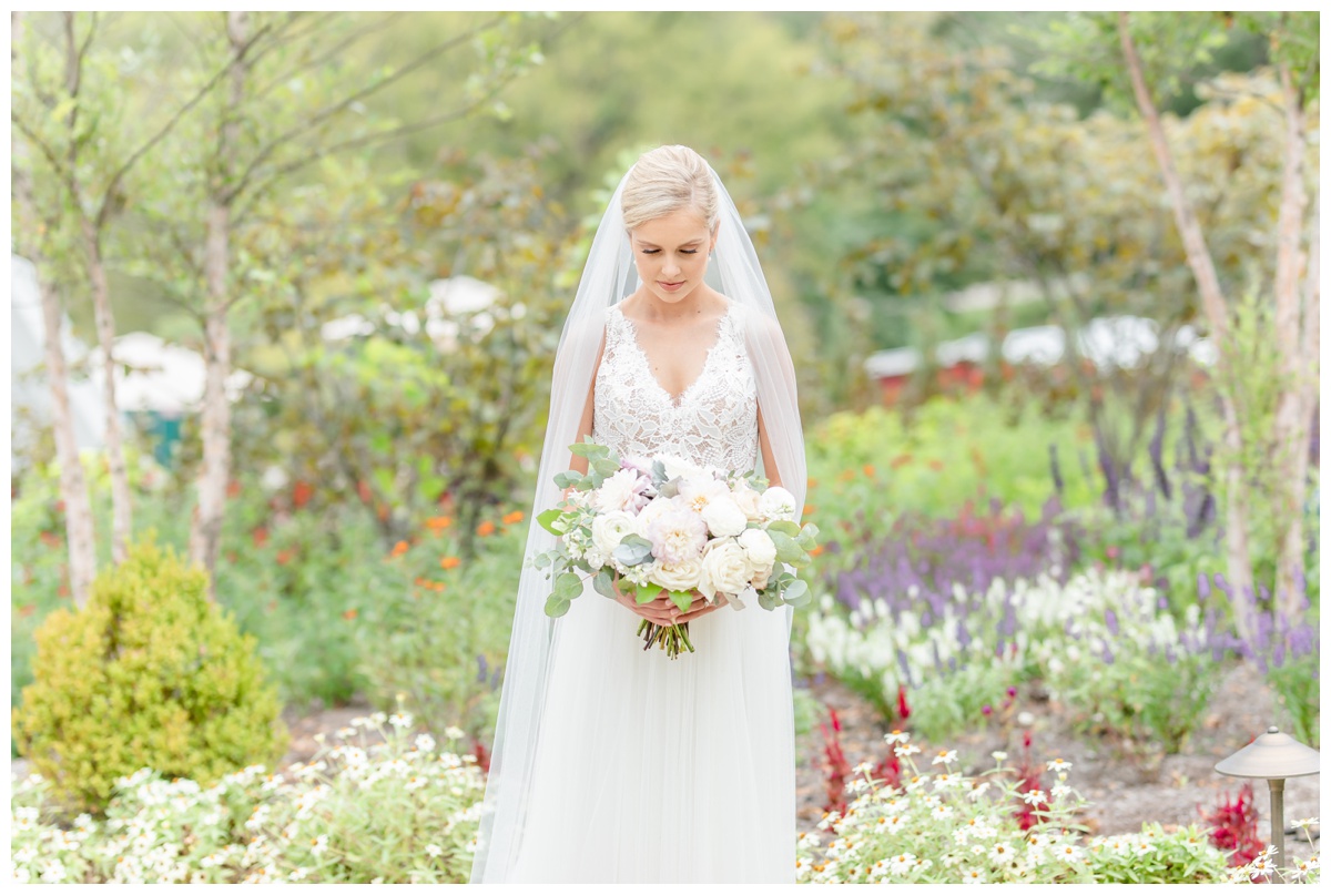 bride looking at bouquet standing in flowers