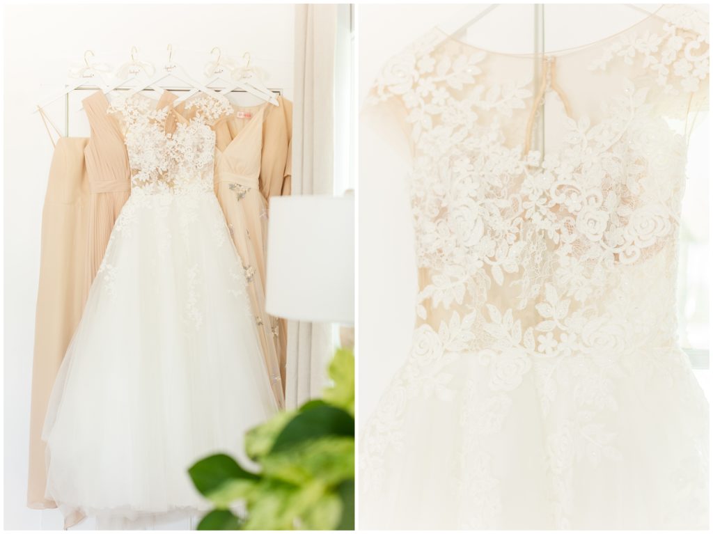 The bride's lace wedding dress is hung in front of the bridesmaids dresses. In the second photo, the bride's lace wedding dress is hung on a white custom hanger in front of a window.