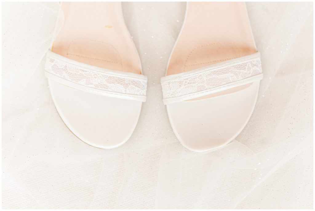 The bride's white and lace wedding shoes are displayed on a white background, including the wedding veil. 