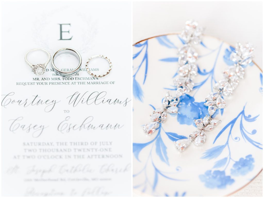 A white gold and diamond engagement ring and wedding band, together with the white gold men's wedding band, are displayed on a the black and white wedding invitation. 2nd photo: the bride's wedding earrings are draped over a blue and white ring dish. 