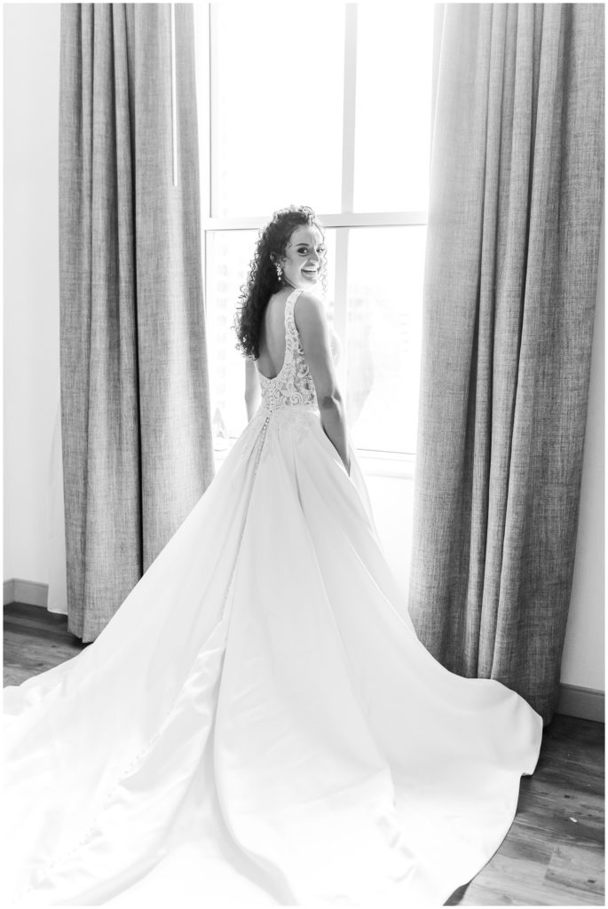 The bride poses in her gown in front of a window. 