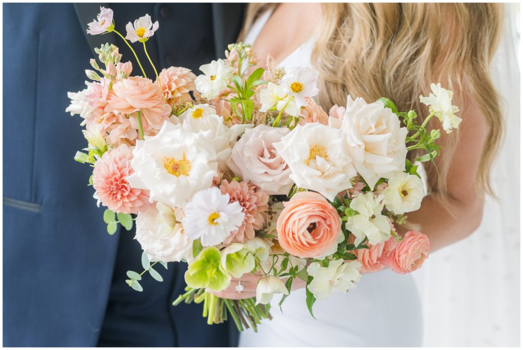 The english garden style bouquet is pictured with pale peaches and pinks, along with bright white and soft green. 