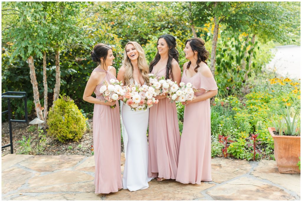 The bride poses with her bridesmaids in their blush pink dresses. 
