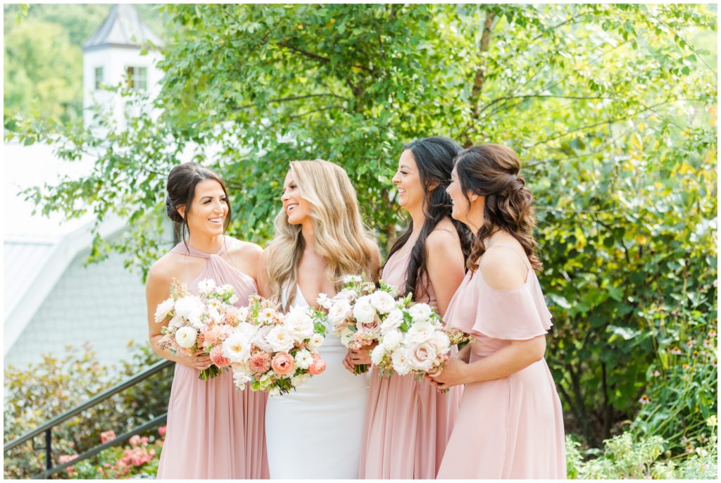 The bride poses with her bridesmaids in their blush pink dresses. 