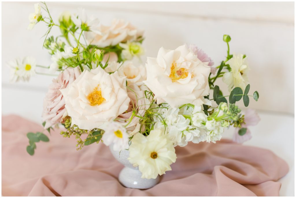 The english garden style arrangement  is pictured with pale peaches and pinks, along with bright white and soft green.